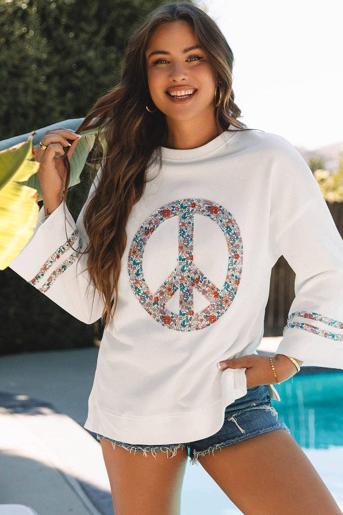 white sweatshirt with a floral peace sign centered in the front.  Bell sleeves wtih 2 floral matching stripes on each side and side waist slits.