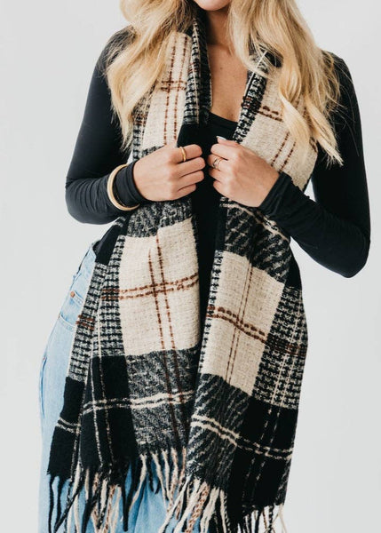 A plaid scarf in black and white with a hint of brown and fringe/tassels