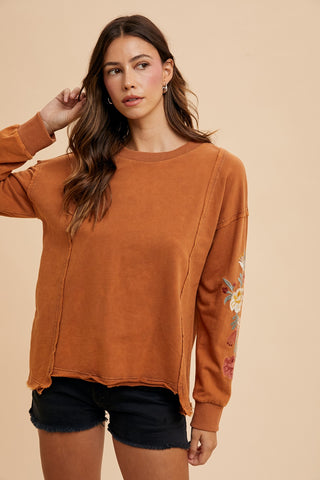 caramel color sweatshirt like top with long floral embroidered sleeves and a round neckline