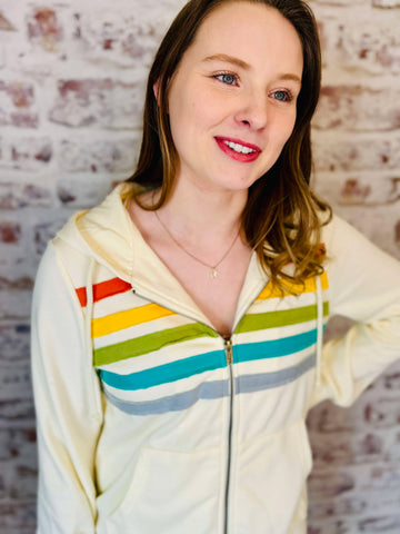 Cream color hoodie with fabric stripes across the chest in red, yellow, green, blue and gray.   drawstring hood and zippered