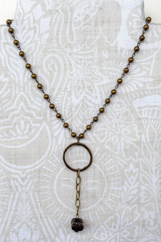a short bronze necklace with a lobster clasp and bronze beads. at the bottom there is a lariat bronze charm.
