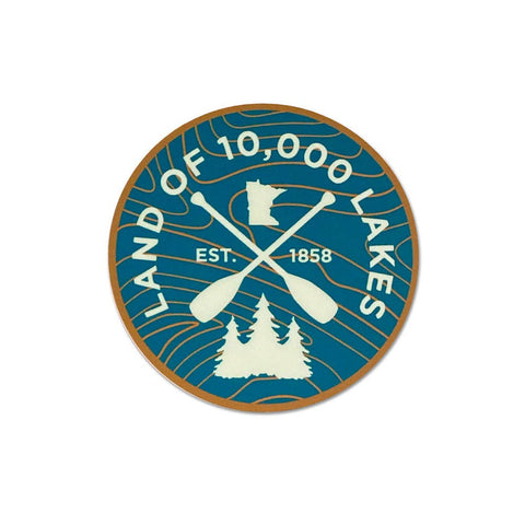 Circular bumper style sticker with 'Land of 10,000 Lakes' text, crossed paddles, and trees on a blue background.